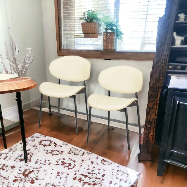 Leather curved back dining side chairs in room with wood table and interior design elements