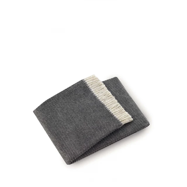 Dark gray links pattern throw blanket on floor with wallet and linens