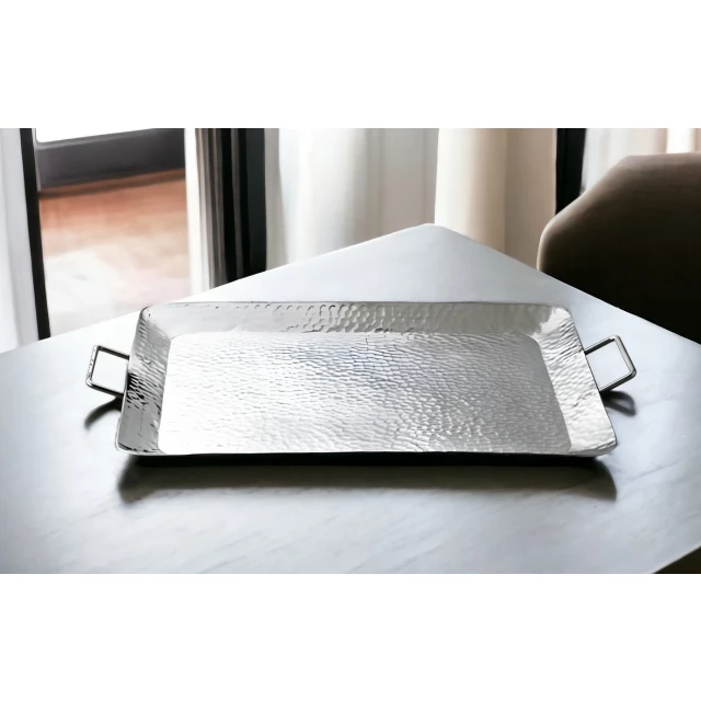 silver hammered metal serving tray with handles on wooden surface
