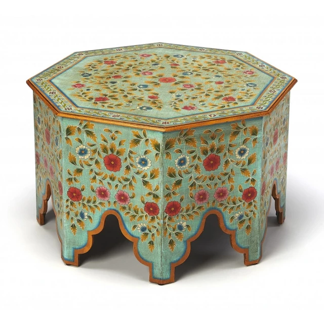 Hand painted coffee table with dishware on top and chairs around in a furniture setting