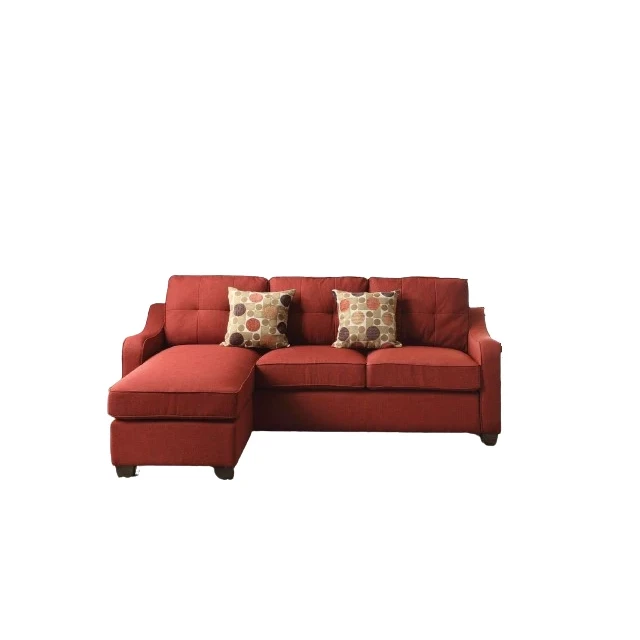 Red linen L-shaped sofa chaise with pillows and wooden accents in a studio setting