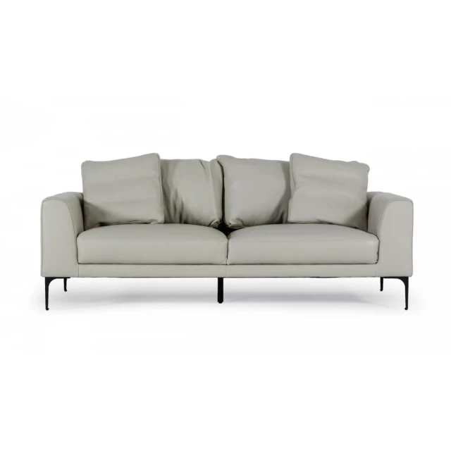 Contemporary light grey leather sofa with comfortable cushions and wooden accents in a studio setting