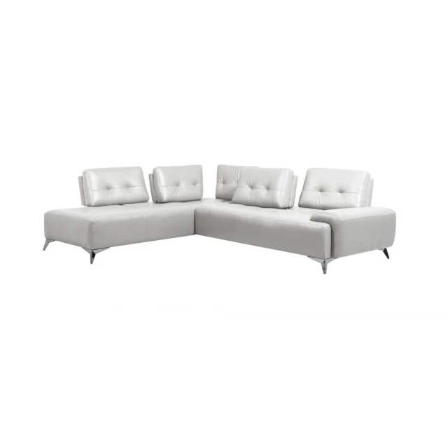 White leather L-shaped couch with pillows in a living room setting