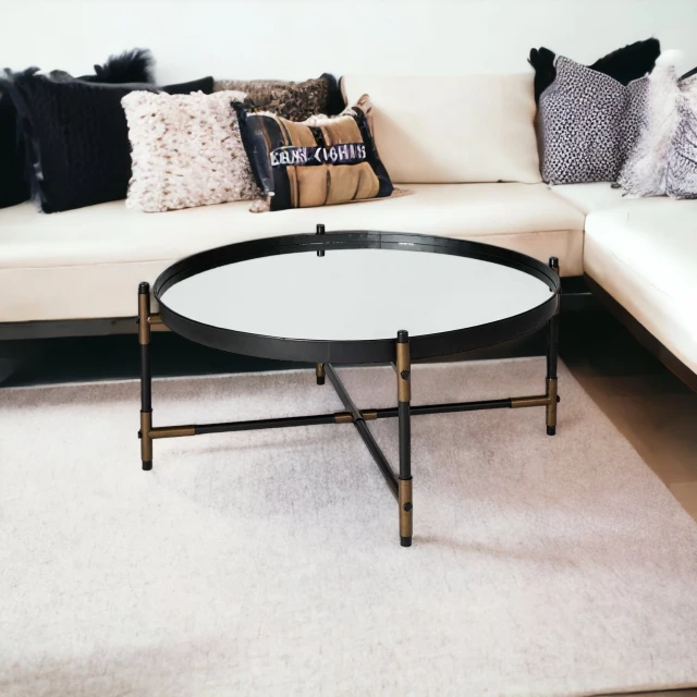 Bronze glass metal round coffee table with black rectangle pillow on white couch in furniture showroom
