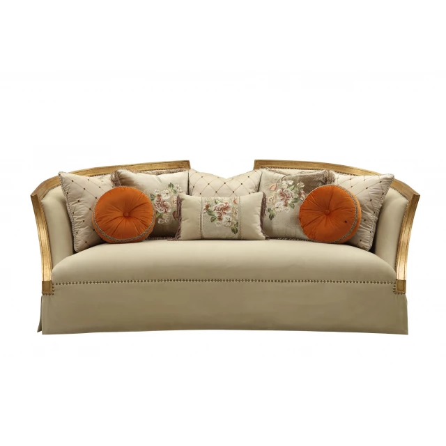 Gold upholstery sofa with wood leg trim and pillows on a comfortable studio couch.