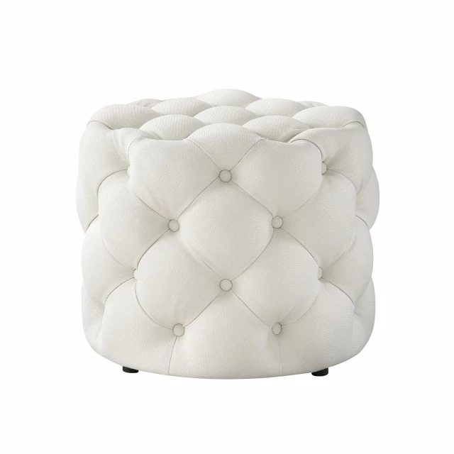 White linen tufted round ottoman in a cozy room setting with soft lighting and comfortable furnishings