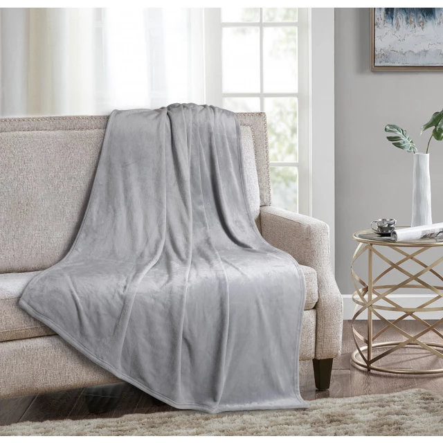 Grey solid anti microbial oversized throw on a wooden couch in a comfortable interior design setting