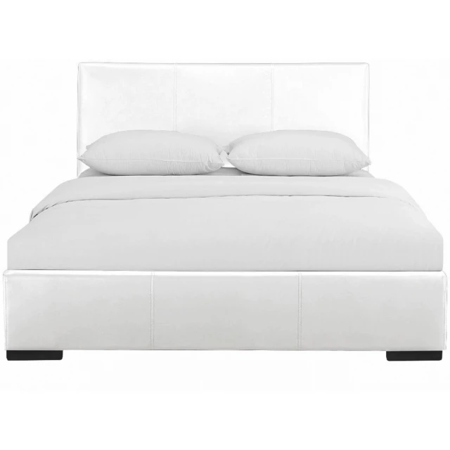 White upholstered king platform bed in a modern bedroom setting