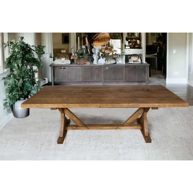 Reclaimed wood trestle base dining table in an interior design setting with plant and wood flooring