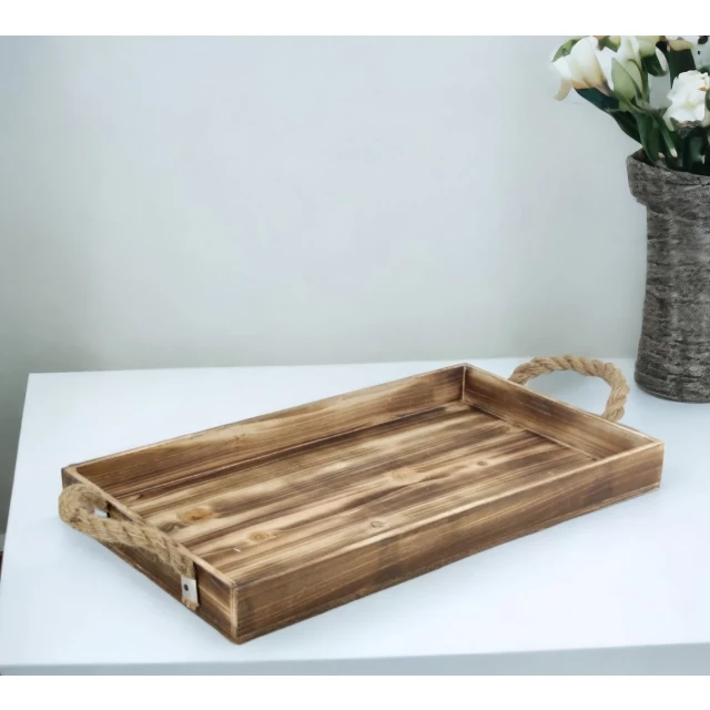 brown wooden tray with rope handles on hardwood table with flowers and plants