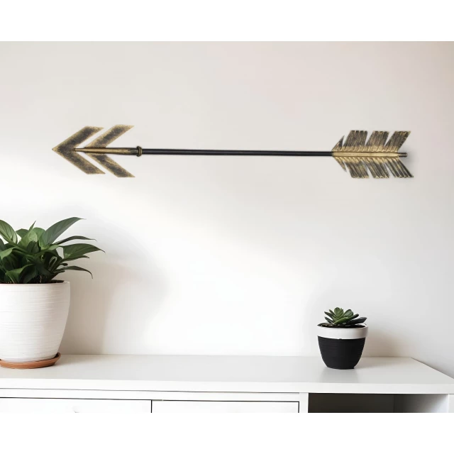 burnished gold metal arrow wall decor with houseplant and flowerpot in interior design setting