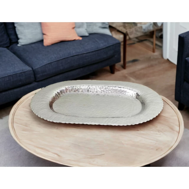 oval stainless steel hammered serving tray on wooden table with dishware