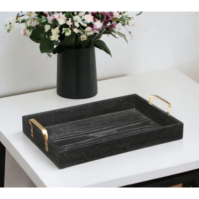 black wooden tray with gold handles and flowerpot on wood table
