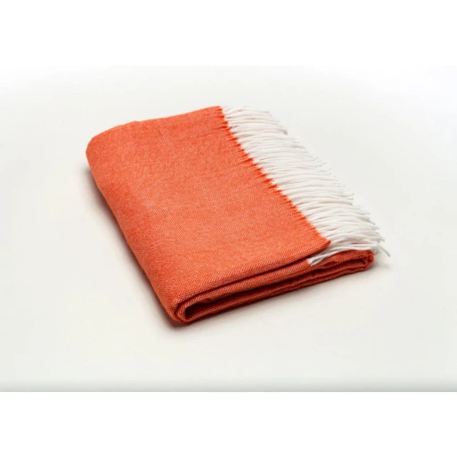 Orange soft acrylic herringbone throw blanket on wood flooring with electric blue fashion accessory