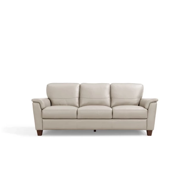 Beige leather sofa with pillows and wooden accents in a comfortable studio couch design