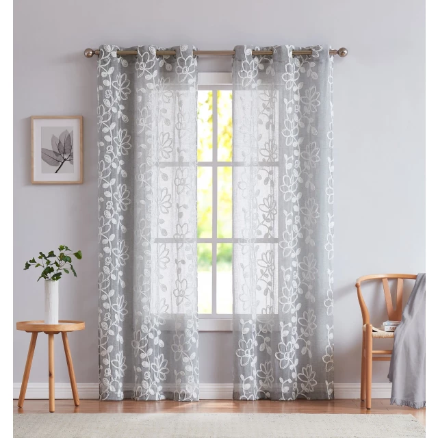 Silver floral embroidered window panels displayed in a room with wooden furniture and soft lighting
