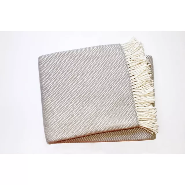 White dreamy soft herringbone throw blanket on wooden chair with patterned linens and metal tableware