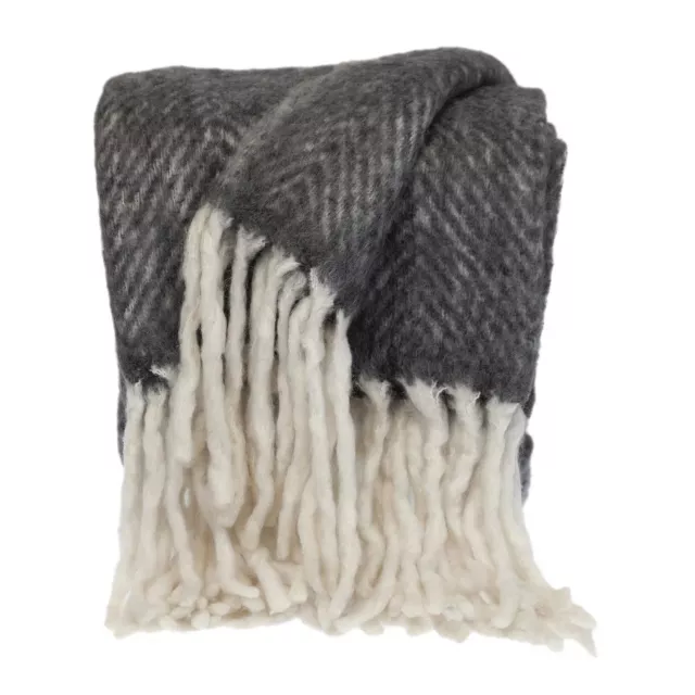 Black & white handloomed mohair throw blanket with wool and fur textures on wooden trunk.