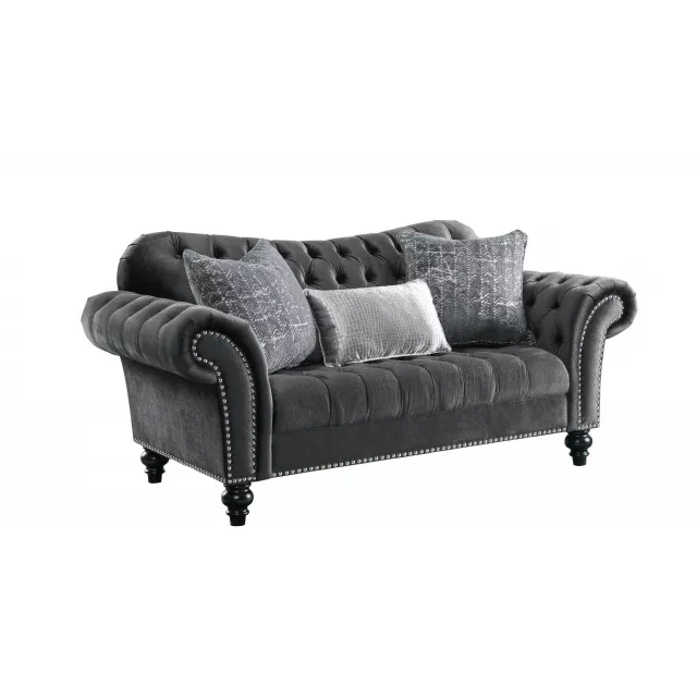 Gray black velvet loveseat with toss pillows in a comfortable studio setting