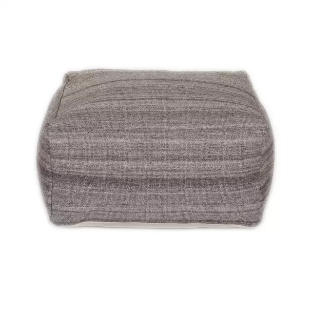 Stone gray brown woolen pouf resembling tire in hardwood setting