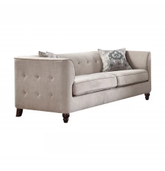 Tan velvet sofa with black toss pillows and beige wood accents