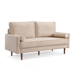 Velvet dark brown sofa with toss pillows and wooden legs in a studio setting