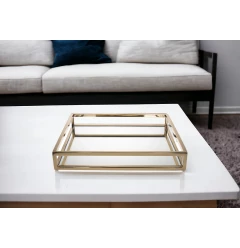 gold square metal serving tray on white couch with wooden table in background