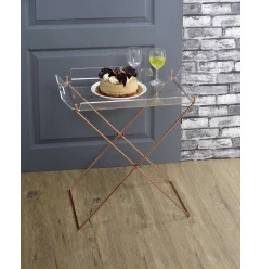 Clear glass gold serving cart with tableware on wood flooring