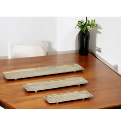 gold rectangular metal serving trays on wooden table with plants