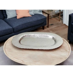oval stainless steel hammered serving tray on wooden table with dishware