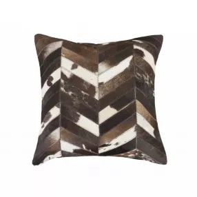 Brown chevron cowhide throw pillow on wood surface with patterned design