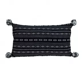 Black and gray pom throw pillow on wicker outdoor furniture with pattern design