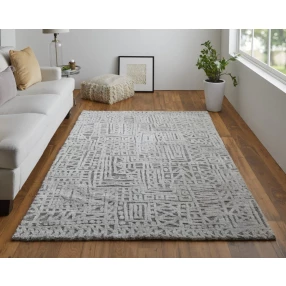 silver geometric stain resistant area rug with plant and window in background